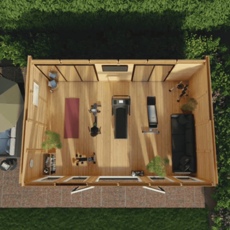 Top-down view of a wooden shed with furniture and items inside, surrounded by greenery.