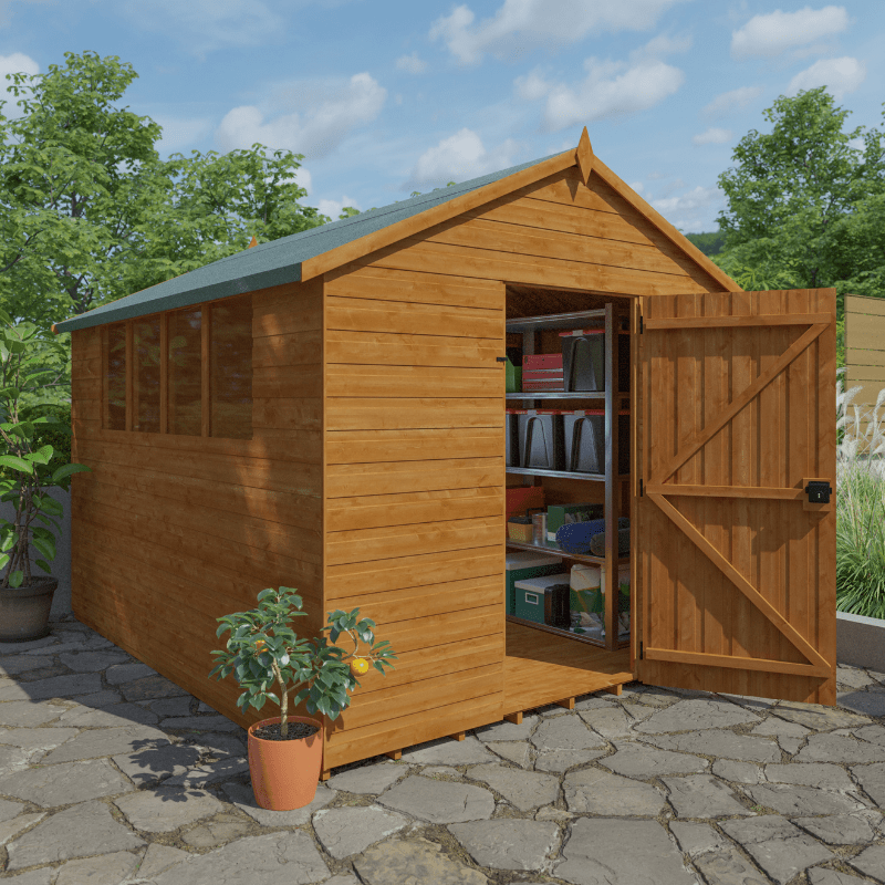 Wooden shed with open door on a stone patio, surrounded by greenery