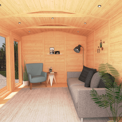 Wooden cabin interior with a gray sofa, armchair, and small table.