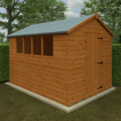 Wooden shed with a green roof on a grassy area with trees in the background
