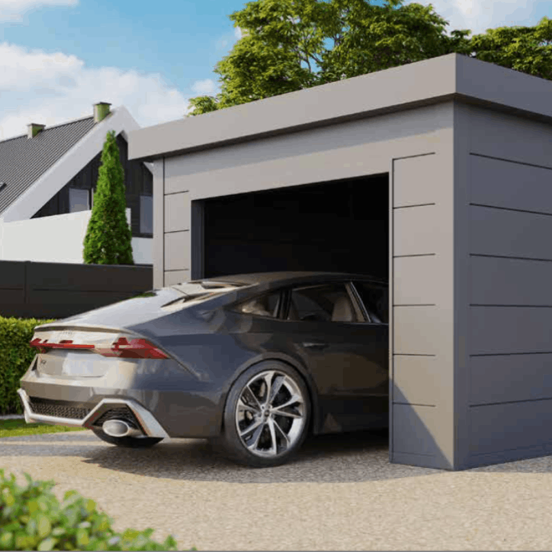 Modern gray car parked in an open gray garage with a house and trees in the background.